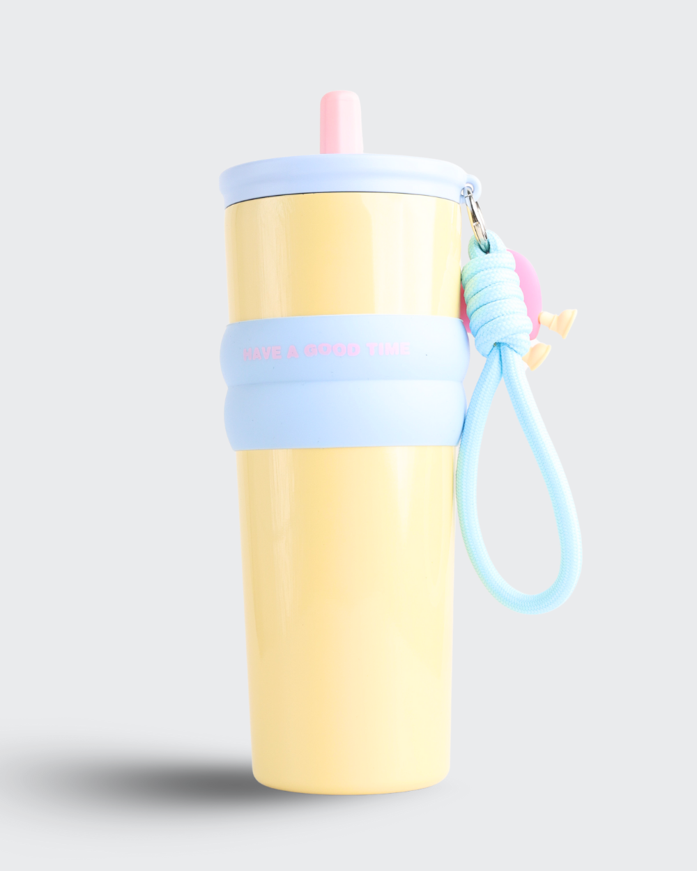 Yellow tumbler with a blue strap and pink straw on a light gray background