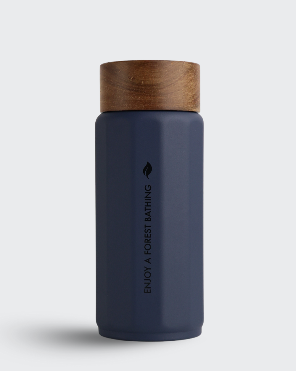 Navy blue bottle with wooden cap on a light gray background