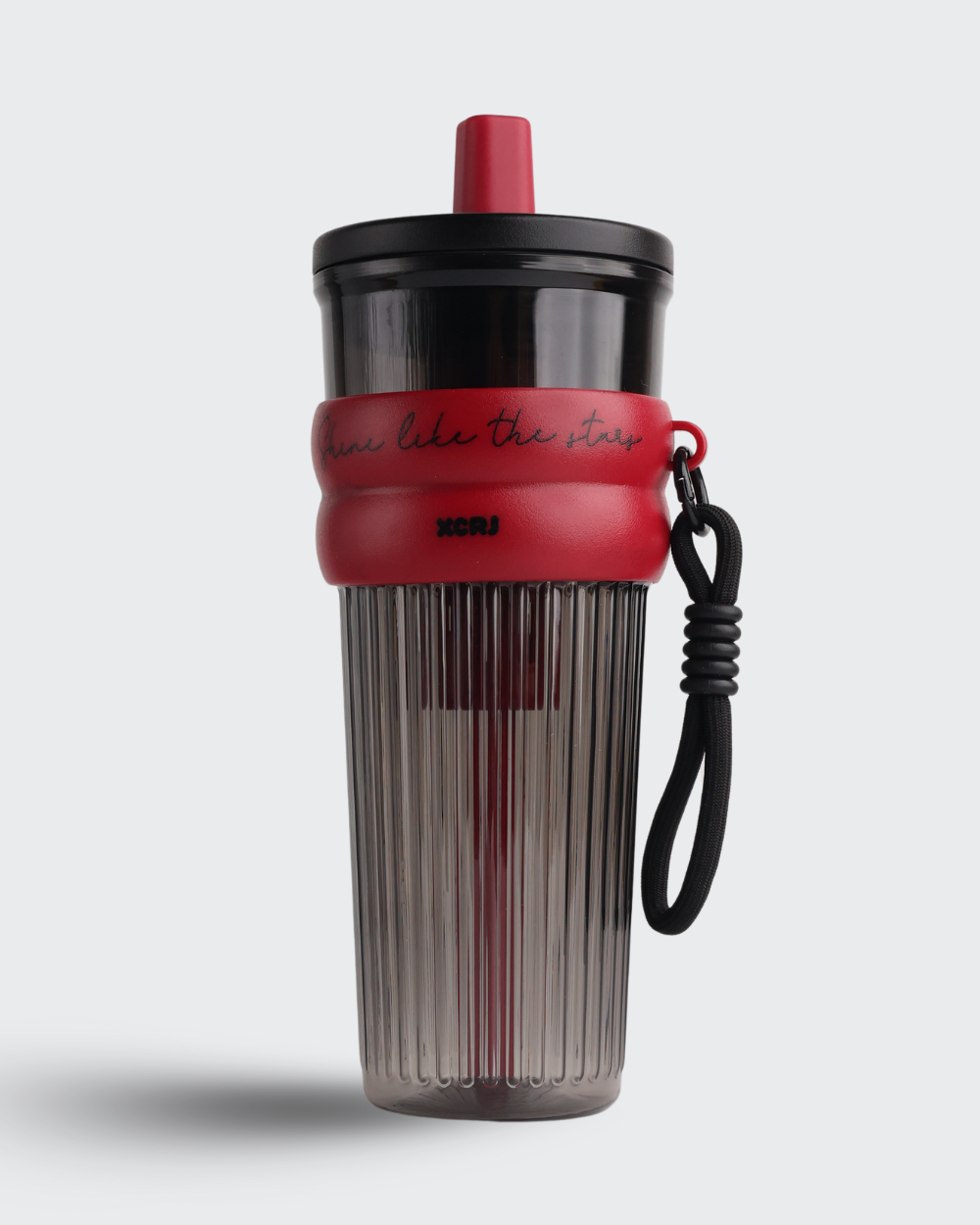 Clear tumbler with red lid and black strap on a white background